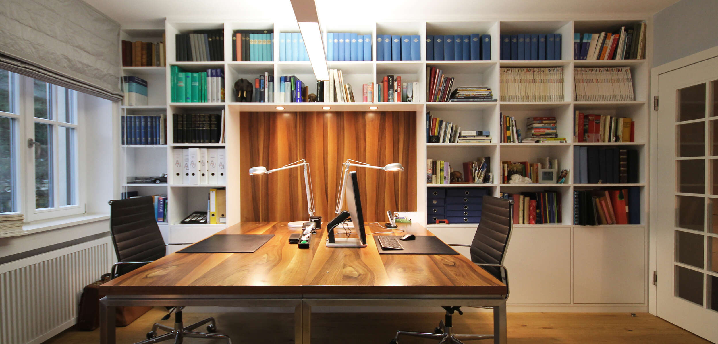 Modernes Arbeitszimmer mit minimalistischem Design, einschließlich eines eleganter Schreibtischs, Regals und Stuhl in München.