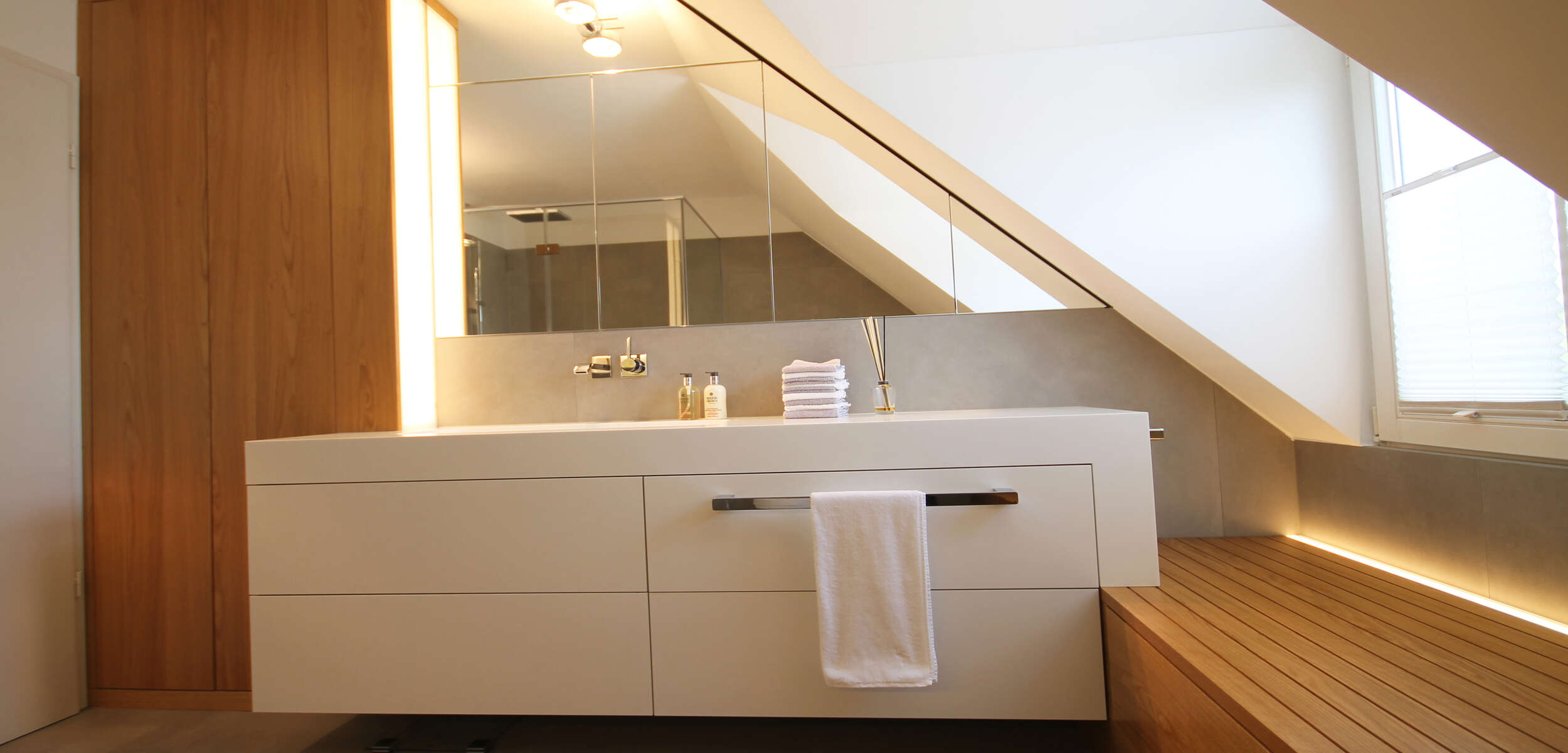 Stilvolles Badezimmer Interieur mit modernem Waschtisch, beleuchtetem Spiegel und eleganten Accessoires, gestaltet von einem Innenarchitekten in München.