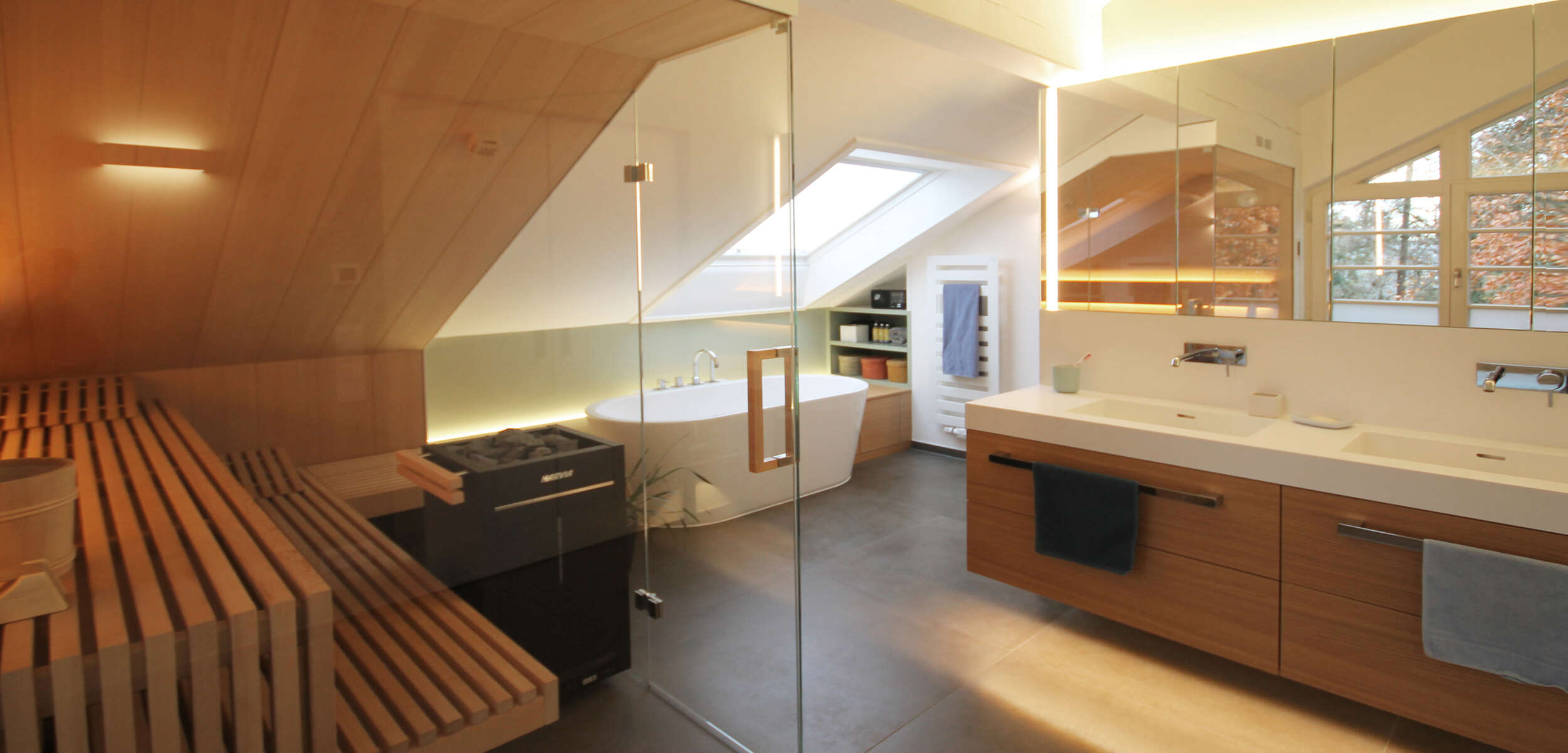 Modern gestaltetes Badezimmer mit Sauna, minimalistischem Waschtisch und warmen Holzelementen als Ausdruck exquisiten Münchner Innenarchitekturstils.