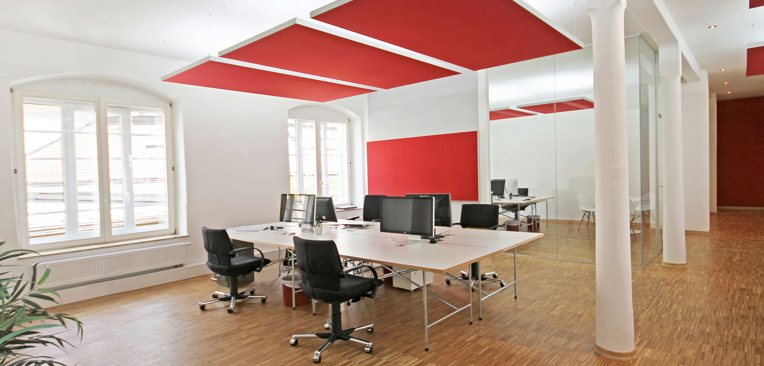 Modernes Büro mit hellen Möbeln und Akustikpaneelen, professionell geplant von einem Innenarchitekten aus München.