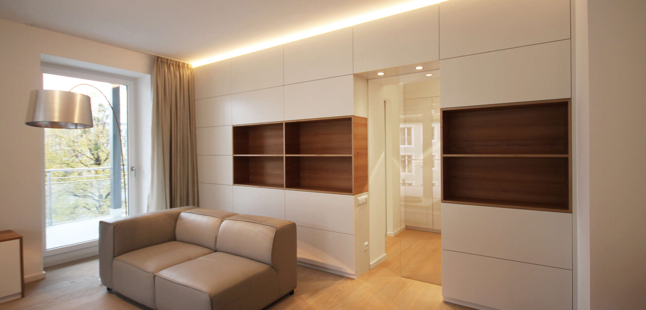 Modernes Wohnzimmer Design mit eleganten Einbaumöbeln und Glas-Schiebetür, kreiert von einem Innenarchitekten aus München.