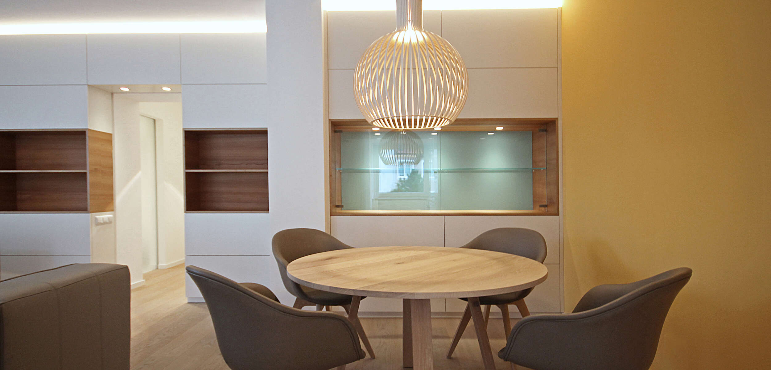 Modernes Interior Design für Essbereich mit minimalistischer Vitrine, hellen Farben und einzigartiger Beleuchtung.