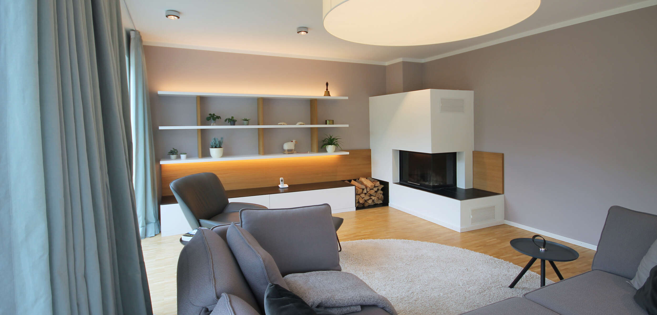 Edles Wohnzimmer Interieur in München mit modernem Kamin, strukturierter Wanddekoration und stilvoller Einrichtung designed von einem Innenarchitekten.