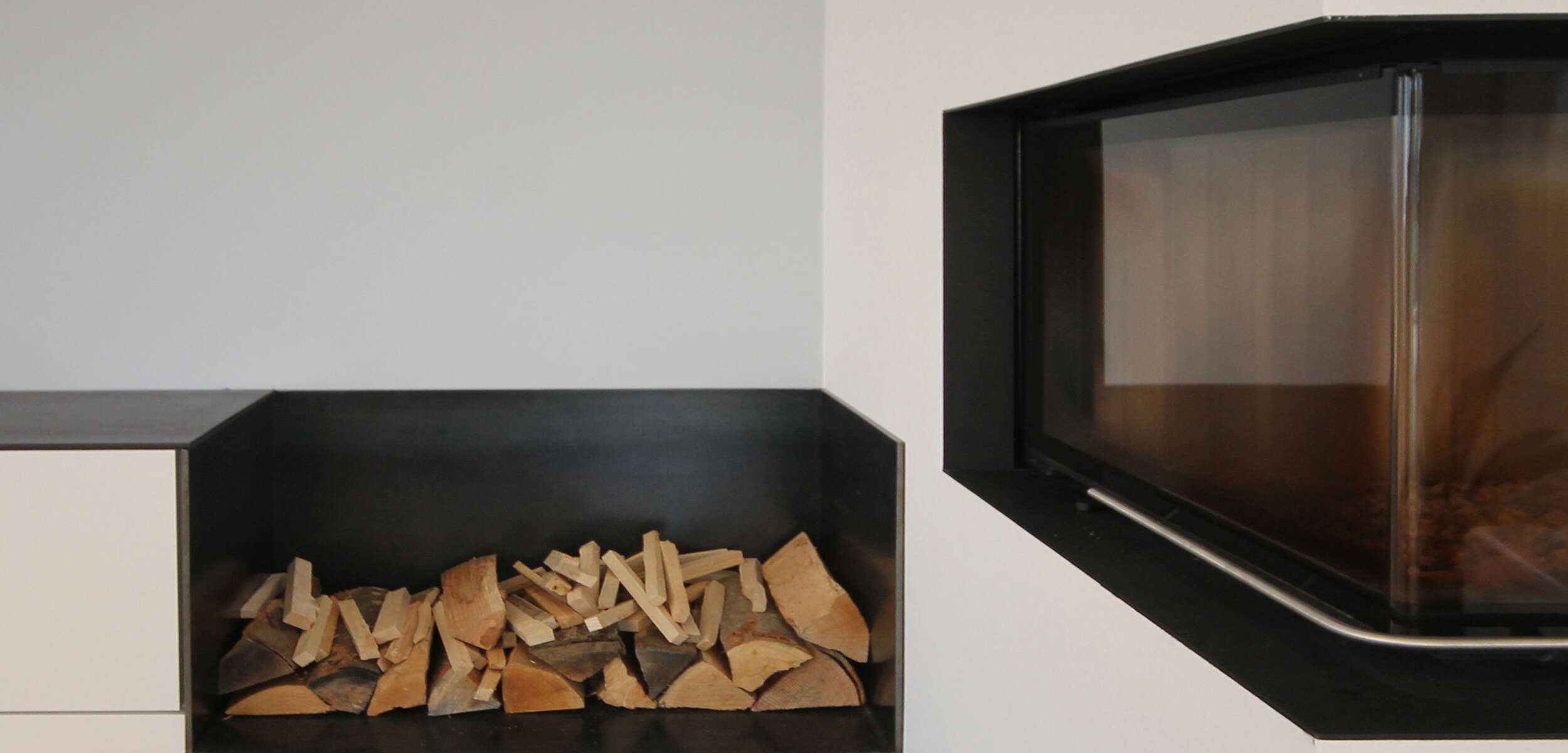 Elegantes Wohnzimmerdesign mit modernem, minimalistischem Kamin und stilvoller Holzlagerung durch einen Innenarchitekten in München.