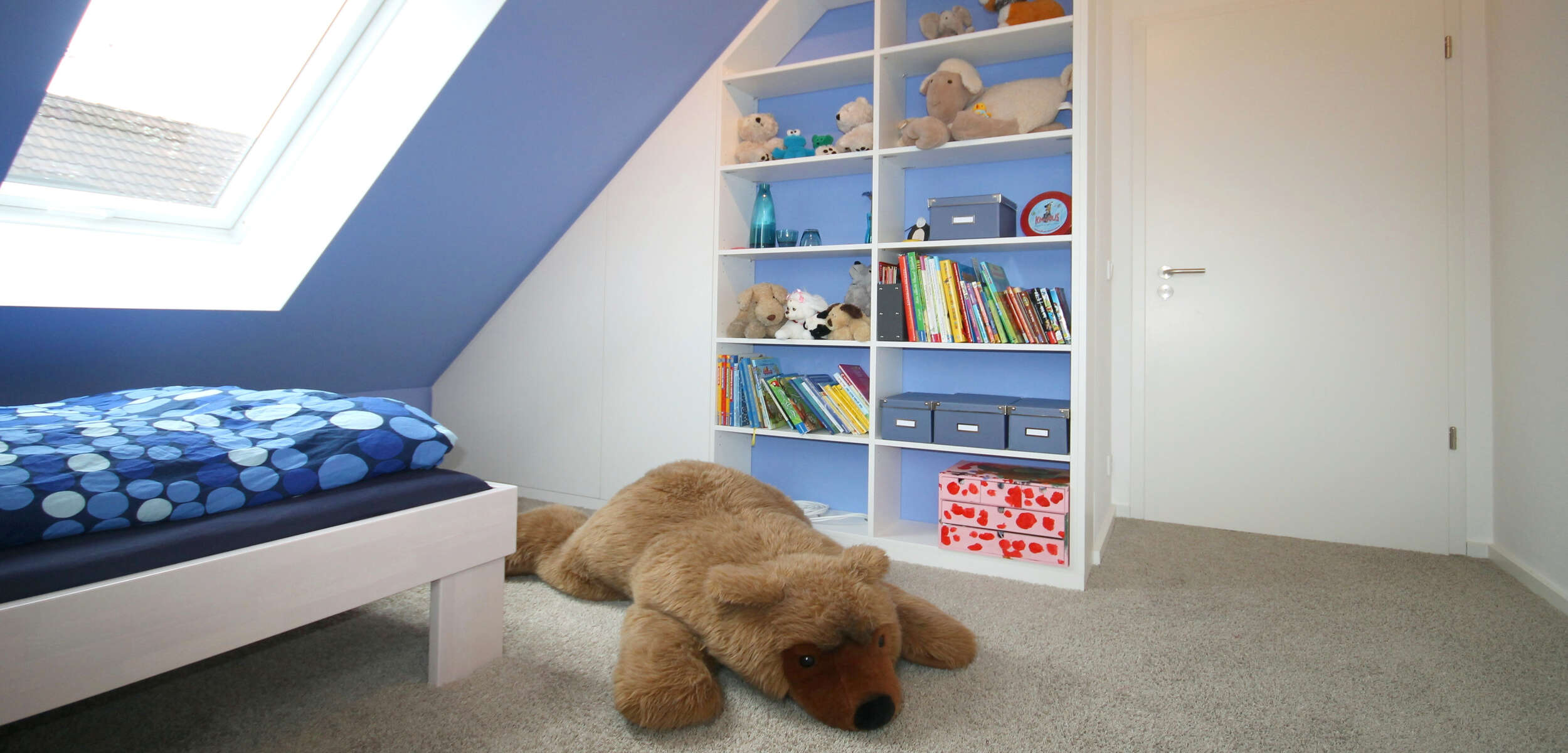Modern und hell gestaltetes Kinderzimmer, in München, mit vielseitigem Spielzeugregal und ansprechenden Farbakzenten durch Innenarchitektur-Experten.