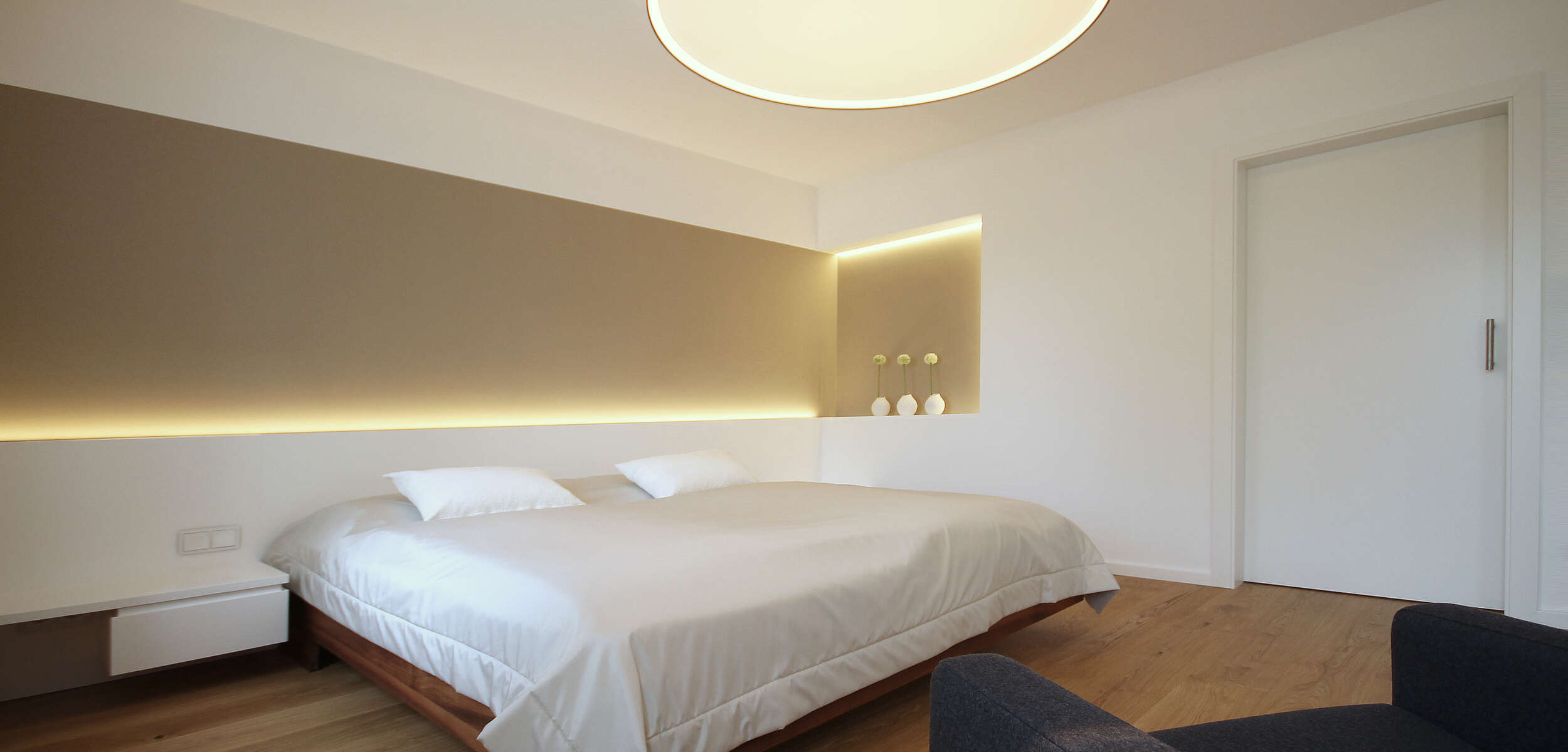 Modernes Schlafzimmer-Design mit komfortablem Bett, Nachttischen und dezenten Einbauschränken in einem umgebauten Einfamilienhaus in München.