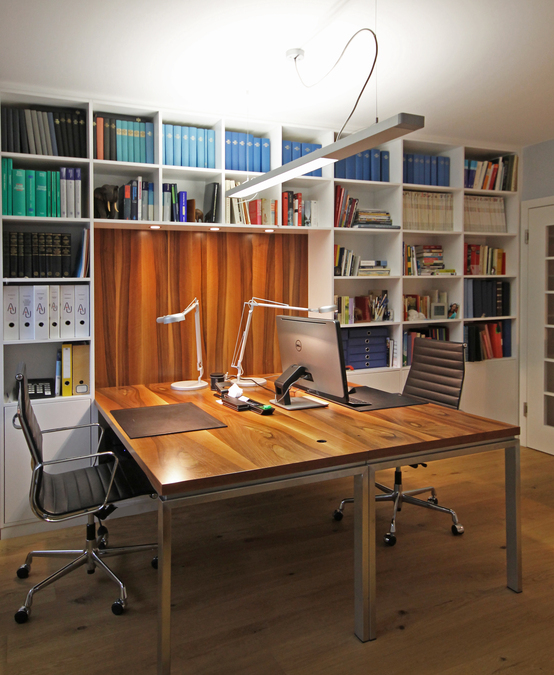 Der Schreibtisch mit zwei Arbeitsplätzen ist aus Nussbaum gefertigt, die Tischplatte wird als Rückwand im Regal weitergeführt, Schrankbeleuchtung.