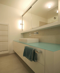 Der Waschtisch ist mit einem Aufsatzbecken und einer Wandarmatur ausgestattet. Der über die Raumbreite durchlaufende Spiegelschrank trägt eine direkte und indirekte Beleuchtung.