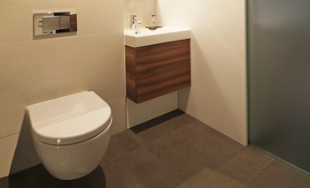 Das Handwaschbecken mit einem Umterbauschrank ist in eine Nische eingepasst, das WC-Becken als Tiefspüler hängt an der Installationswand.