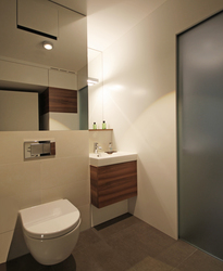 Raumhohe Spiegelflächen verdoppeln den Raumeindruck, eine Glasschiebetür grenzt den Hauswirtschaftsraum ab und transportiert Tageslicht ins Gäste-WC.