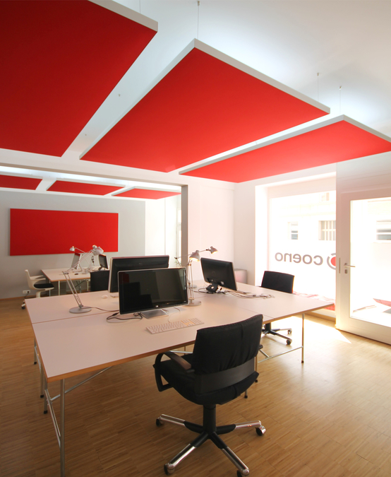 Auf Wänden wurden Schallabsorber in Form von Wandpaneelen aufgehängt. Das Farbkonzept des Entwurfes nimmt die Farben des Firmen-CI in Akustikelementen, Wand und Decke auf.