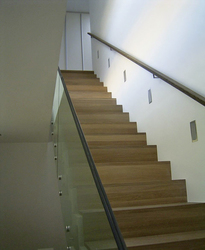 Die Treppe führt von der Diele ins Obergeschoss. Stufen der Betontreppe sind mit Räuchereiche belegt, der Handlauf besteht aus Edelstahl, die Brüstung aus Glas.