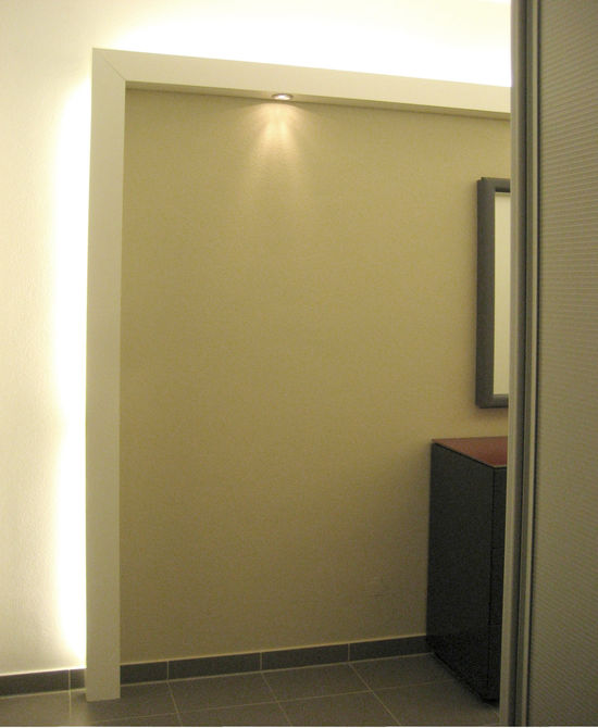 Die Lichtleiste mit einer Oberfläche aus weißem Lack versteckt die Leuchtstoffröhren und führt das indirekte Licht bis zum Boden. Eingelassene Strahler setzen Akzente.