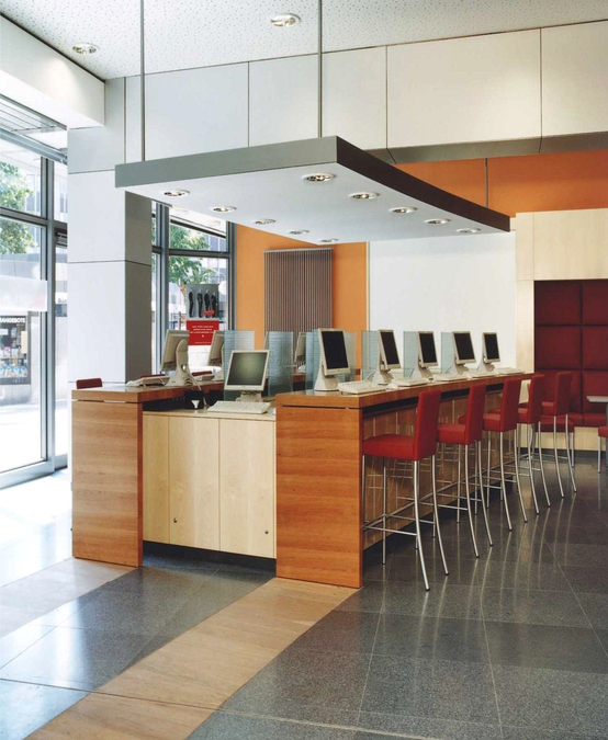 Die Theken stellen Internetplätze für Kunden sowie Arbeitsplätze für Schulungen und Seminare bereit. Das Deckensegel trägt arbeitsplatzgerechte Einbauleuchten.