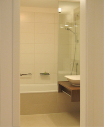 Das Badezimmer hellen Fliesen bringt auf kleinster Fläche Badewanne, Dusche, Waschbecken, WC-Becken, Handtuchtrockner, Spiegelschrank und eine Waschmaschine unter.