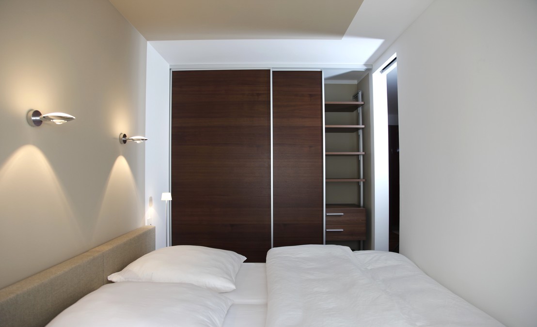 Das Bett passt genau zwischen die Wandscheiben an Kopf- und FuÃende. Die Wandleuchten setzen Akzente. Der SchiebetÃ¼renschrank nutzt die Raumnische optimal.