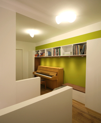 In der Diele des Obergeschosses wurde ein Klavier in die Regalwand integriert. Eine Kommode wird als Sitzfläche genutzt. Der Flur wird zum Aufenthaltsbereich und Musikzimmer.