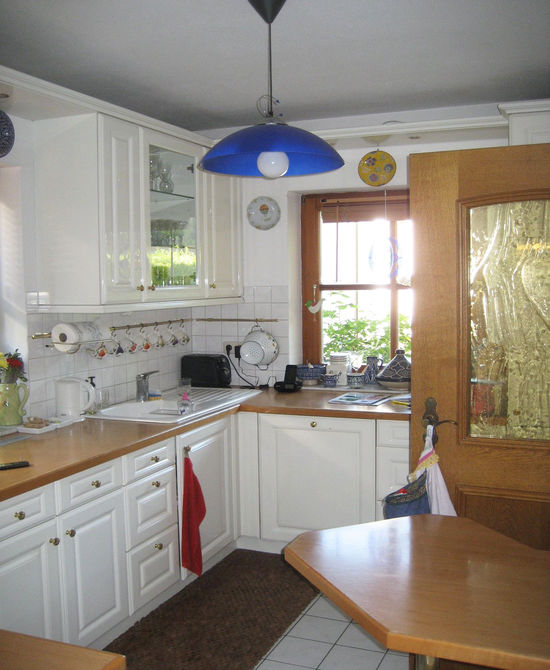 Die Küche im Landhausstil wurde ausgebaut und durch eine moderne offene Wohnküche mit schlichten weiß lackierten Fronten im Raumkonzept von Innenarchitekt Andreas Ptatscheck, München, ersetzt.