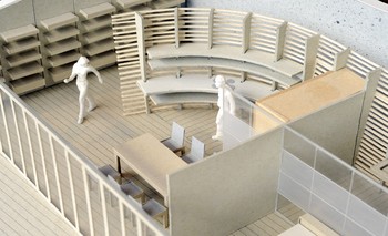 Ein Modell veranschaulicht den Entwurf. Die Küche schmiegt sich mit ihrer Arbeitsplatte an die Rundung der Lamellenwand an. Essplatz an der Außenfassade.