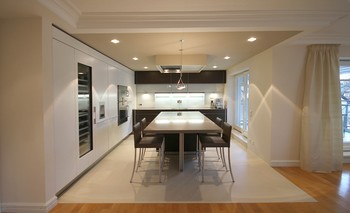 Die Unterseite der Abhangdecke ist sandfarben gestrichen und zitiert den Farbton der Bodenfliesen, gemeinsam spannen sie die Küchenfläche als Raum im Wohnraum auf.