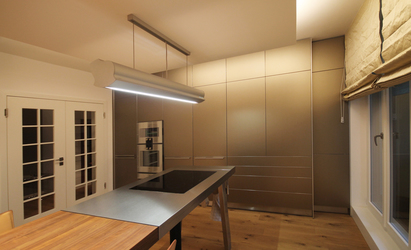 Die bronzefarbenen Aluminiumfronten der Küchenzeile zeigen einen leichten Schimmer und spiegeln durch die Lichtreflexion die Farben der Umgebung.