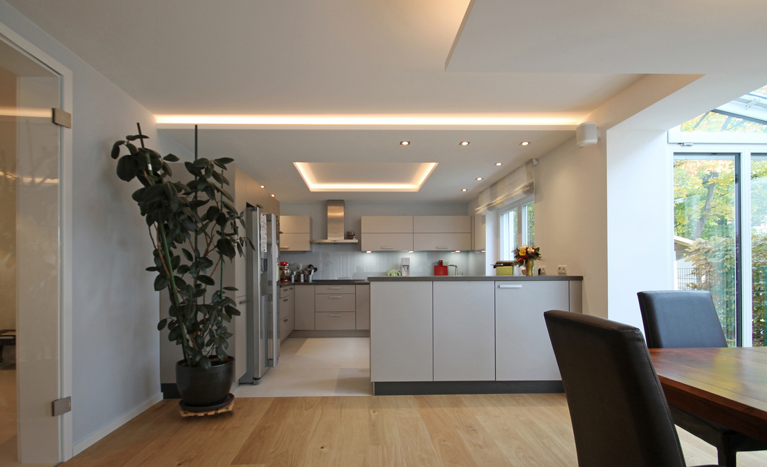 Durch eine Abhangdecke mit Lichtvoute und indirekt beleuchtetem Deckenfeld inszeniert Innenarchitekt Andreas Ptatscheck, München, die Küche im Wohnraum.