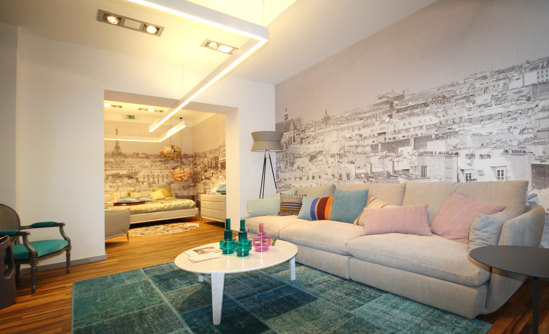 Zentrales Element im Eingangsbereich des Showrooms ist eine Abhangdecke in Betonoptik, die auf drei markanten Stützen ruht und eine indirekte Beleuchtung trägt.