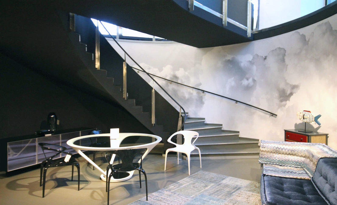 Punktgenaue Lichtspots und Strahler inszenieren die farbenfrohen Möbel vor dem dunklen Hintergrund und lassen sie strahlen. Glaswände strukturieren den Verkaufsraum.