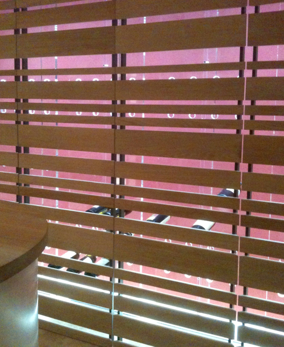 Die Türen vor den Weinregalen bestehen aus massivem Eichenholz. Die Holzlatten haben unterschiedliche Abstände, durch diese hindurch sind die Weinflaschen erkennbar.