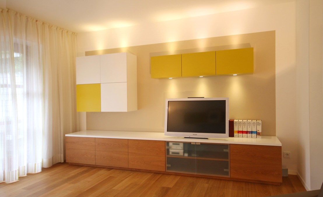 Die Medienwand bringt technisches Gerät wie TV, Videorecorder, Audiogeräte, Receiver unter, ist auf deren Maße abgestimmt, unsichtbare Kabelführung und Belüftung.