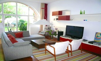 Ecksofa, Sessel und Teppich spannen einen Raum im Raum auf und definieren den Wohnbereich zusammen mit dem Hängeregal und dem Lowboard mit TV-Schrank.